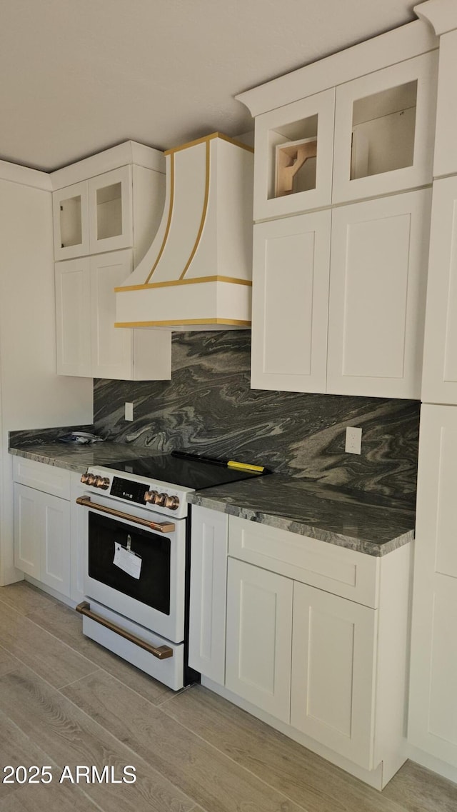 kitchen featuring white electric range, white cabinetry, and custom range hood