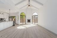 unfurnished living room with beam ceiling, light hardwood / wood-style flooring, and high vaulted ceiling