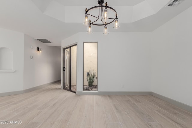 spare room with a notable chandelier and light hardwood / wood-style flooring