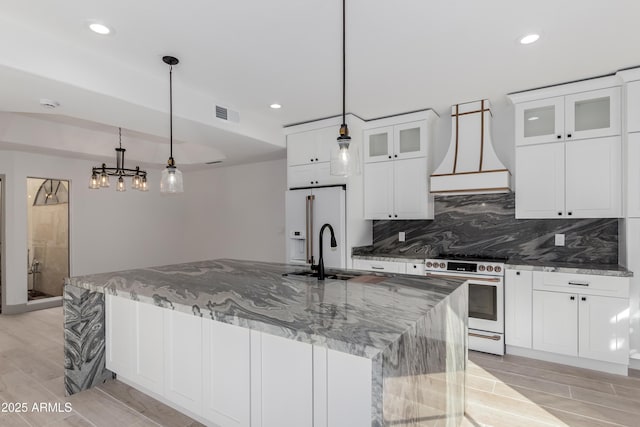 kitchen with premium appliances, pendant lighting, white cabinetry, and dark stone countertops