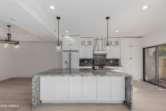 kitchen featuring dark stone countertops, a large island, decorative light fixtures, high quality fridge, and decorative backsplash