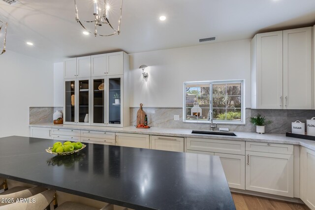 7348 N 9th Pl, Phoenix, AZ 85020 - kitchen with a sink, decorative backsplash, white cabinets, a chandelier, and light wood-style floors