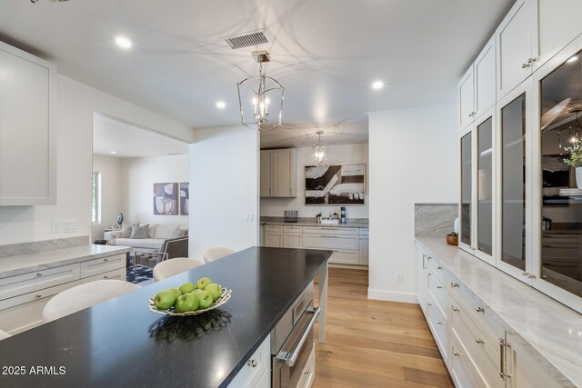 7348 N 9th Pl, Phoenix, AZ 85020 - kitchen with recessed lighting, a chandelier, light wood finished floors, white cabinets, and hanging light fixtures
