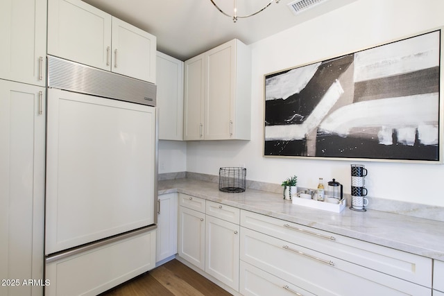7348 N 9th Pl, Phoenix, AZ 85020 - kitchen featuring paneled built in refrigerator, white cabinetry, wood finished floors, and light stone countertops