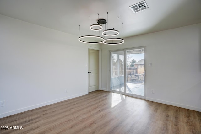 empty room with wood finished floors, baseboards, and visible vents