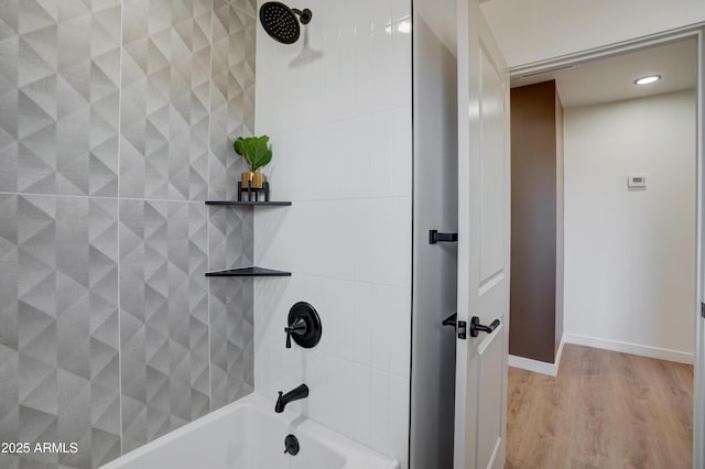 full bath with baseboards, wood finished floors, and bathing tub / shower combination