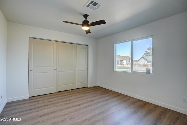 unfurnished bedroom with a closet, visible vents, baseboards, a ceiling fan, and light wood-type flooring