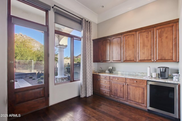 kitchen featuring a wealth of natural light, wine cooler, dark wood finished floors, and light stone countertops