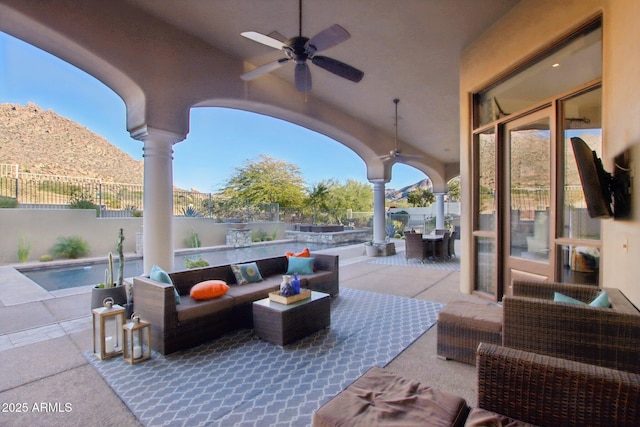 view of patio with a mountain view, outdoor lounge area, ceiling fan, and fence