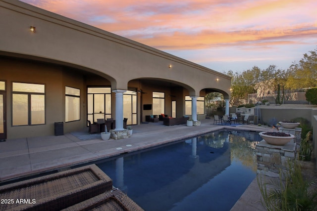 pool at dusk with a patio, a fenced in pool, and fence