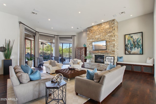 living area featuring a stone fireplace, wood finished floors, and visible vents