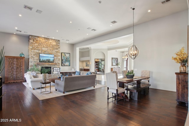 living room with visible vents, a stone fireplace, and hardwood / wood-style floors