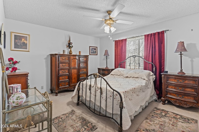 bedroom featuring a textured ceiling, light colored carpet, and ceiling fan