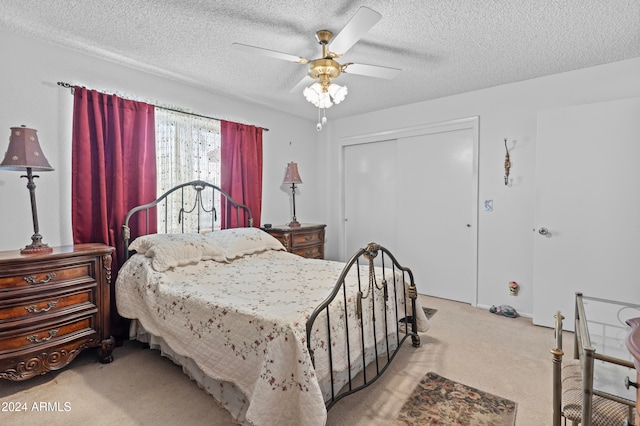 bedroom with a closet, ceiling fan, a textured ceiling, and light colored carpet