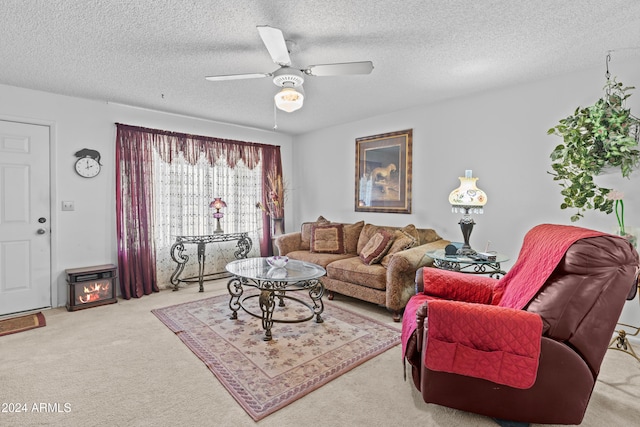 living room featuring ceiling fan, a textured ceiling, a wood stove, and light colored carpet