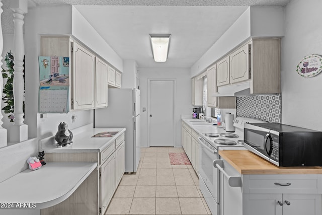 kitchen with butcher block counters, backsplash, sink, light tile patterned flooring, and white appliances