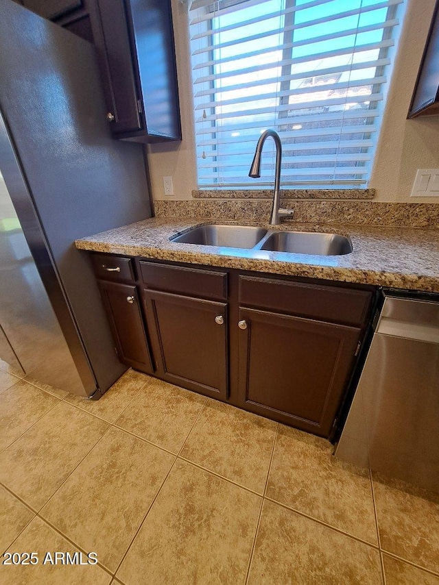 kitchen featuring light tile patterned flooring, appliances with stainless steel finishes, dark brown cabinetry, and sink