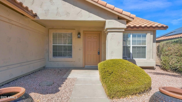 doorway to property with a tile roof and stucco siding