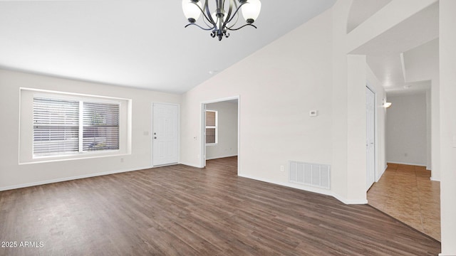 spare room featuring high vaulted ceiling, a notable chandelier, wood finished floors, visible vents, and baseboards