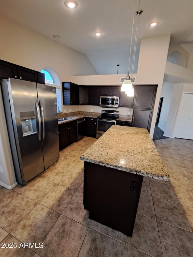 kitchen featuring hanging light fixtures, light tile patterned floors, appliances with stainless steel finishes, and light stone counters