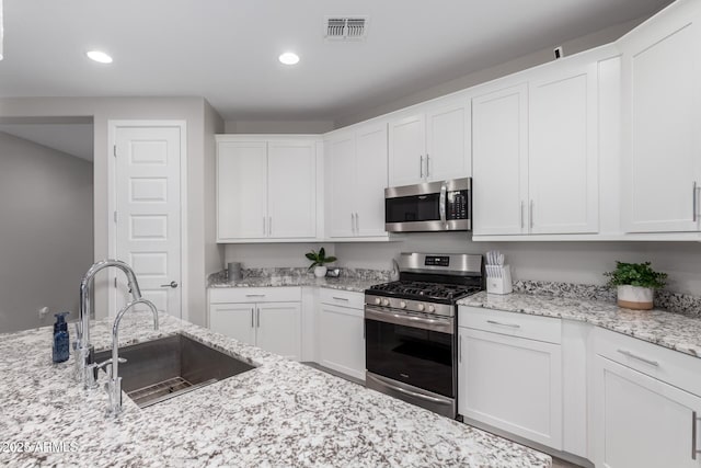 kitchen featuring sink, stainless steel appliances, white cabinets, and light stone countertops