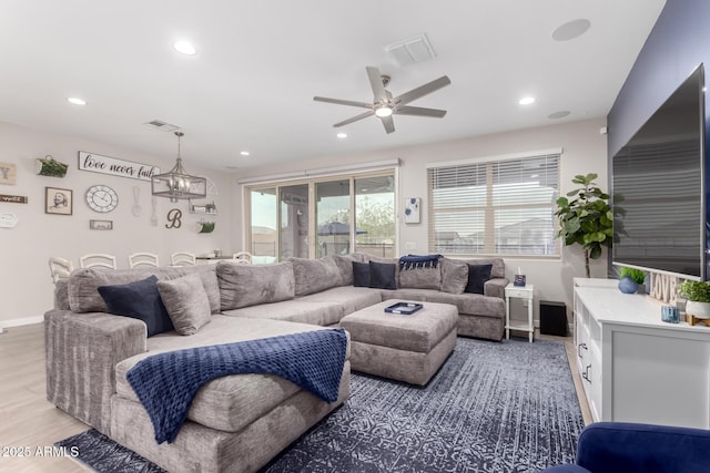 living room with hardwood / wood-style floors and ceiling fan with notable chandelier