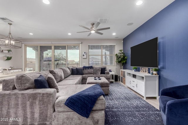 living room with wood-type flooring and ceiling fan with notable chandelier