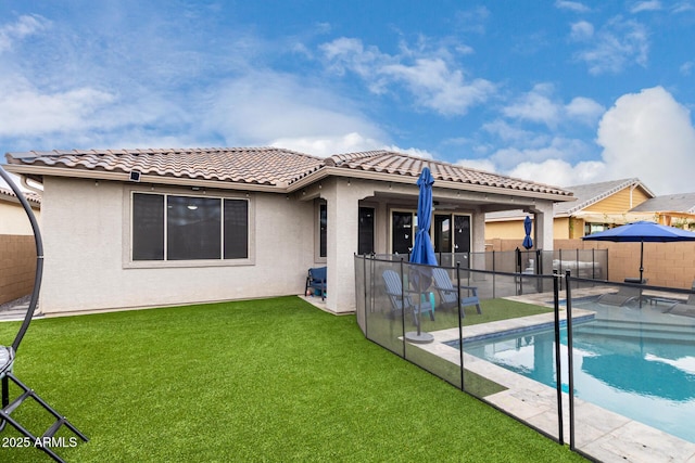 back of house with a fenced in pool, a lawn, and a patio