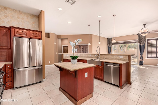 kitchen featuring sink, hanging light fixtures, stainless steel appliances, a breakfast bar area, and light tile patterned flooring