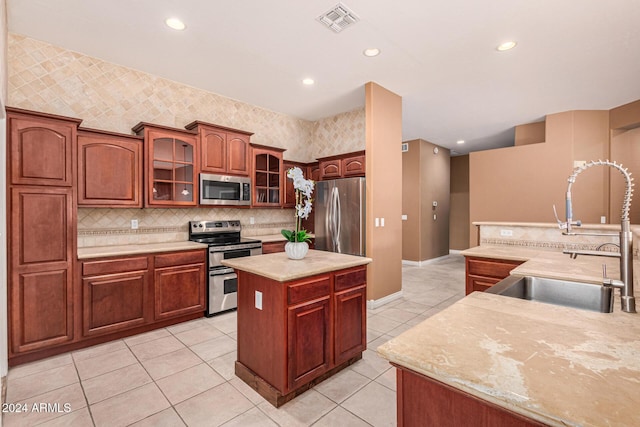 kitchen with decorative backsplash, stainless steel appliances, sink, light tile patterned floors, and a kitchen island