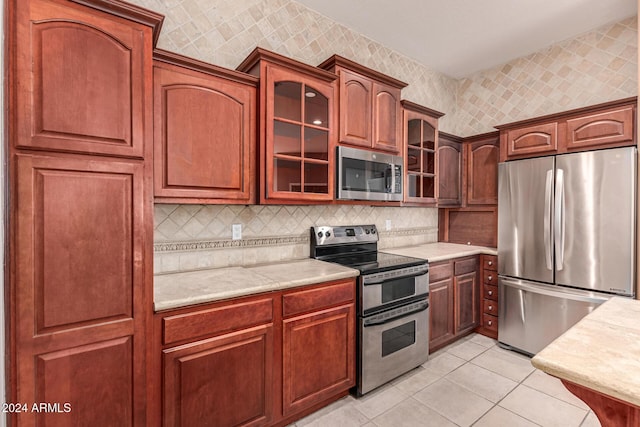 kitchen with light tile patterned flooring, appliances with stainless steel finishes, and tasteful backsplash