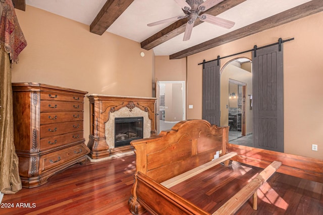 living room featuring ceiling fan, a barn door, hardwood / wood-style flooring, a premium fireplace, and beamed ceiling