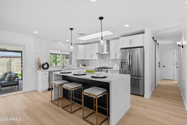 8732 E Arlington Rd, Scottsdale, AZ 85250 - kitchen with appliances with stainless steel finishes, wall chimney exhaust hood, a sink, a kitchen island, and light countertops