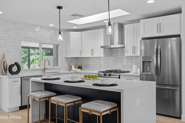 8732 E Arlington Rd, Scottsdale, AZ 85250 - kitchen with appliances with stainless steel finishes, wall chimney range hood, a skylight, a sink, and a kitchen breakfast bar