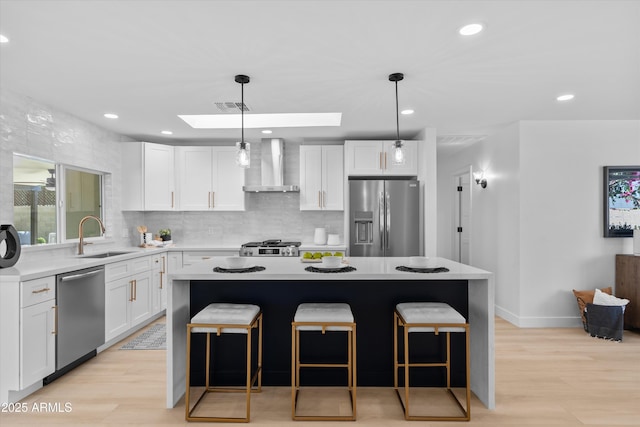 8732 E Arlington Rd, Scottsdale, AZ 85250 - kitchen featuring appliances with stainless steel finishes, wall chimney exhaust hood, a sink, a skylight, and a kitchen island