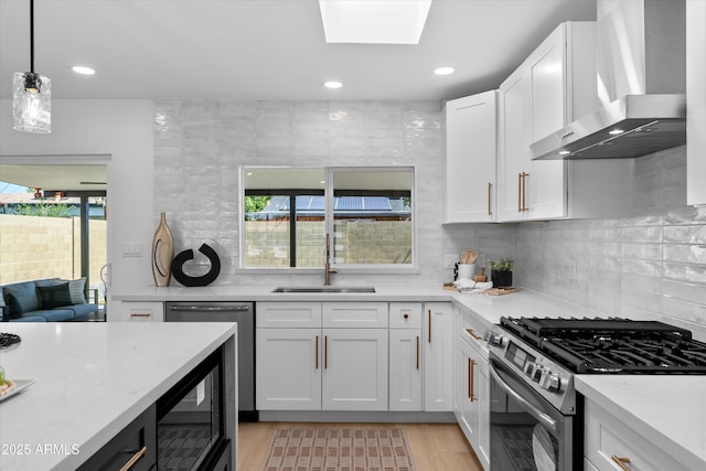 8732 E Arlington Rd, Scottsdale, AZ 85250 - kitchen featuring wall chimney exhaust hood, stainless steel appliances, a sink, light wood-style floors, and white cabinets