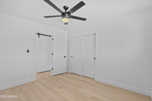 8732 E Arlington Rd, Scottsdale, AZ 85250 - unfurnished bedroom featuring baseboards, a barn door, light wood-type flooring, a closet, and a ceiling fan