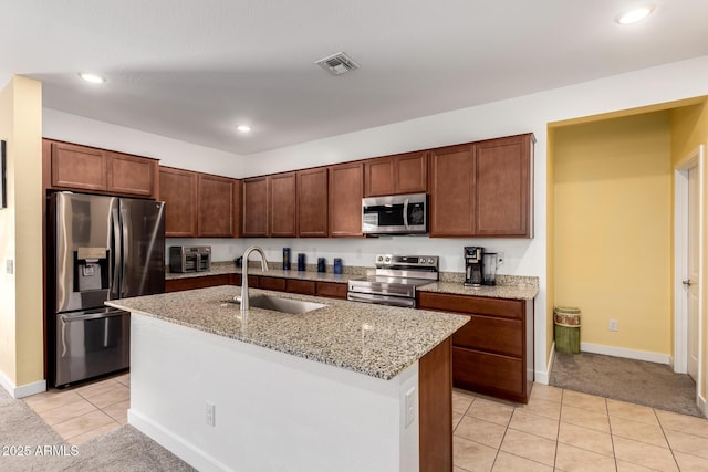 23407 W Winslow Ave, Buckeye, AZ 85326 - kitchen with appliances with stainless steel finishes, a sink, light tile patterned flooring, light stone counters, and a center island with sink