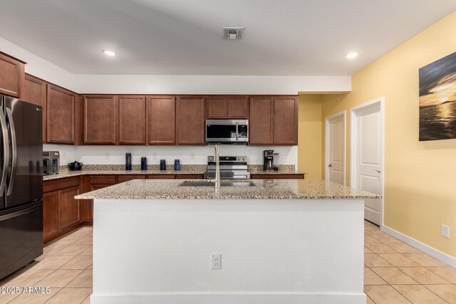 23407 W Winslow Ave, Buckeye, AZ 85326 - kitchen featuring appliances with stainless steel finishes, light tile patterned floors, light stone countertops, a kitchen island with sink, and recessed lighting