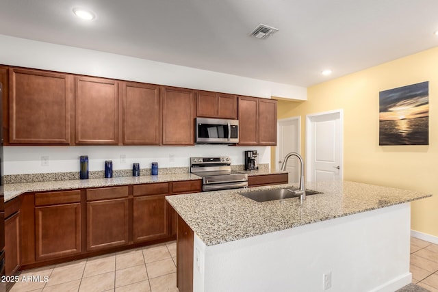23407 W Winslow Ave, Buckeye, AZ 85326 - kitchen with stainless steel appliances, a sink, light tile patterned flooring, light stone countertops, and a kitchen island with sink