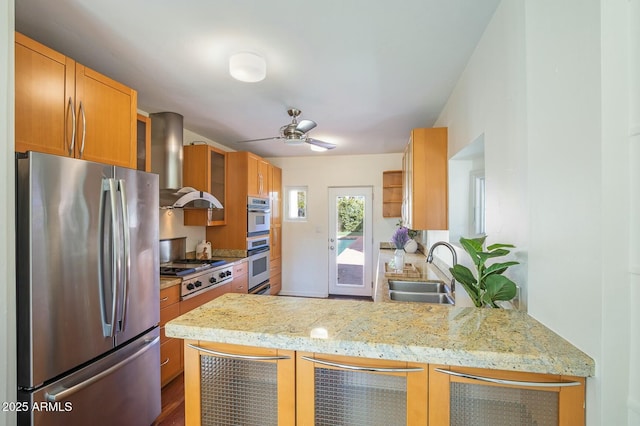 kitchen with sink, appliances with stainless steel finishes, kitchen peninsula, light stone countertops, and exhaust hood