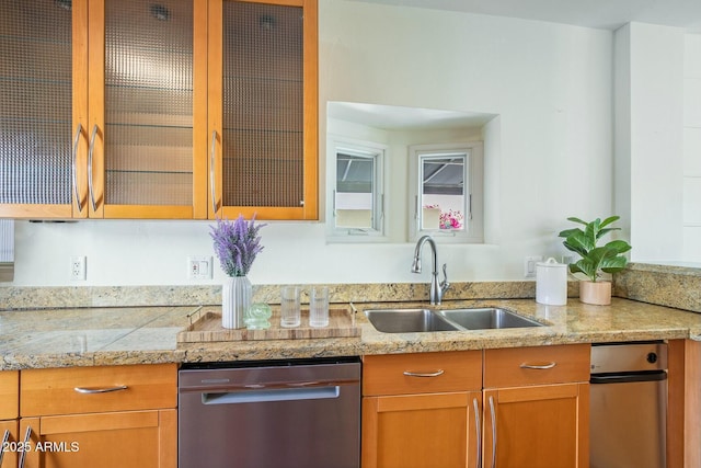 kitchen with light stone countertops, sink, and stainless steel dishwasher