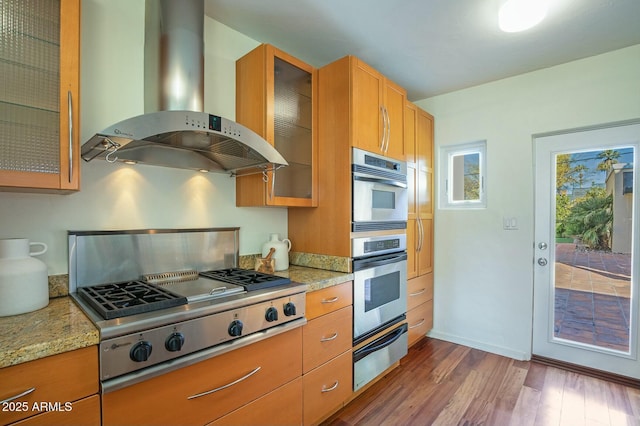 kitchen featuring light stone counters, island exhaust hood, stainless steel appliances, and dark hardwood / wood-style flooring