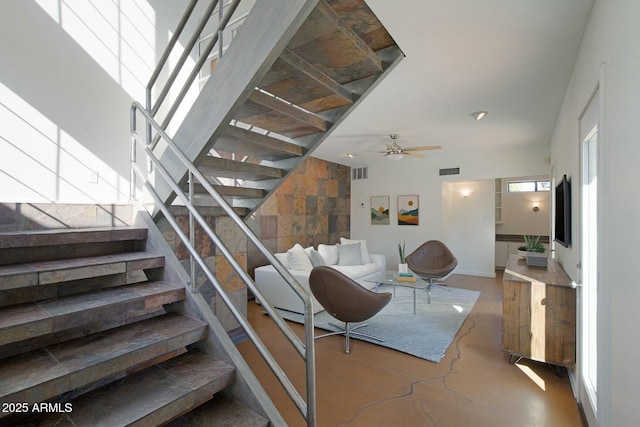 stairway with concrete floors and ceiling fan