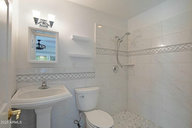 bathroom featuring a tile shower, tile walls, and toilet