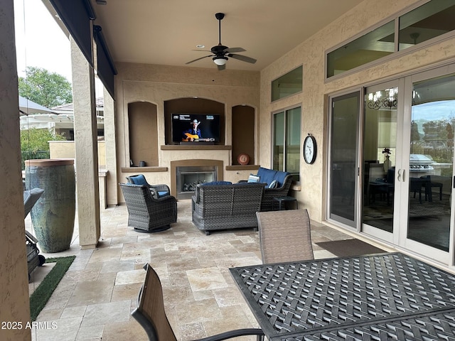 view of patio with ceiling fan and an outdoor living space with a fireplace