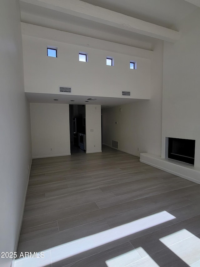 unfurnished living room featuring a fireplace, visible vents, and wood finished floors