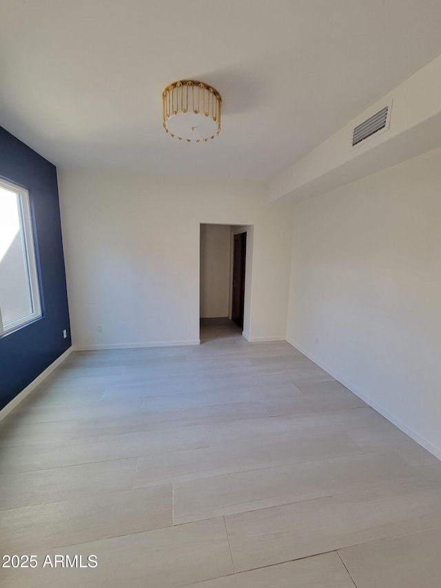 empty room featuring baseboards, visible vents, and light wood-style floors