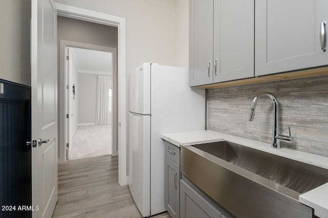 kitchen with light hardwood / wood-style floors, crown molding, sink, and tasteful backsplash