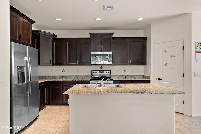 3326 N 31st St, Mesa, AZ 85213 - kitchen with stainless steel appliances, light tile patterned floors, light stone counters, a center island with sink, and dark brown cabinets